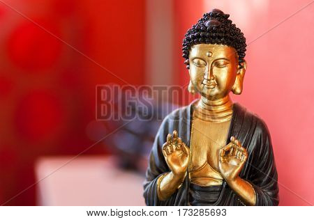 Buddha sculpture in front of a red background