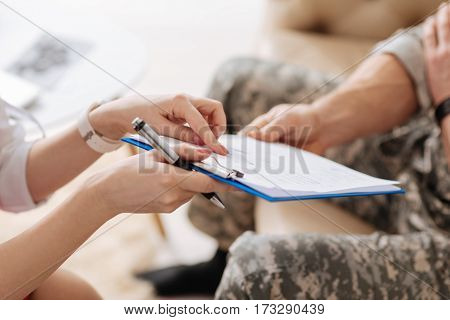 Psychological test. Close up of a sheet of paper being given to a nice military man while having an appointment with a psychologist