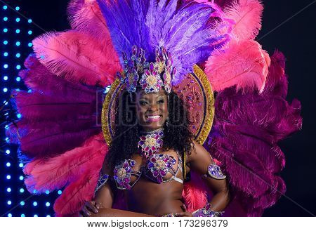 MOSCOW, RUSSIA- JANUARY 2017: Brazilian carnival show. Beautiful girl bright colorful carnival costume dark background. Smiling Afro-Americans woman samba dancer pink carnival costume black background