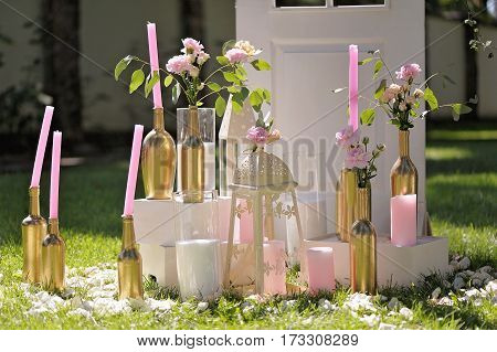 Beautifully Composition Of Candles And Red Flowers On Grass