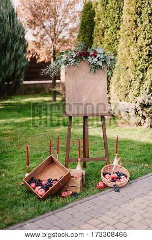 Inviting Banner On Easel With Autumnal Composition Of Red Apples And Dark Blue Grape In Wooden Box O