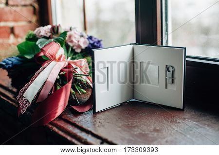 Tenderless bouquet with bow and ribbons in green and pink and blue colours with flash drive package on brown background