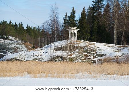 White gazebo on the cliff. Sunny February day. View from the lake Ayranne. Sortavala Karelia