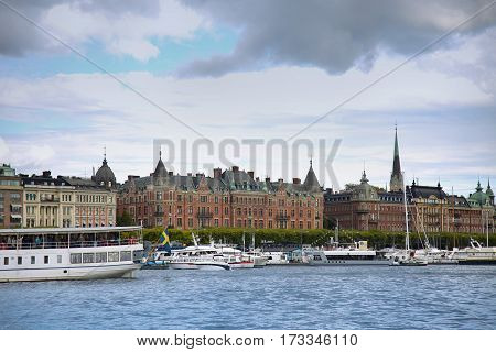 STOCKHOLM SWEDEN - AUGUST 20 2016: Many people walk and visit on Strandvagen street on Ostermalm distric with touristic sightseeing boats in Stockholm Sweden on August 20 2016.