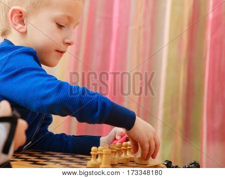 Intelligent smart ass kids games good for brain intelligence concept. Young kid boy playing chess and having fun.