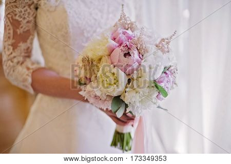 Bride holding delicate and tender marriage bouquet in white and pink colours