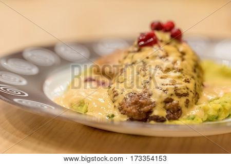 Meat patties or frikadeller in chese and mushroom sauce decorated with berries