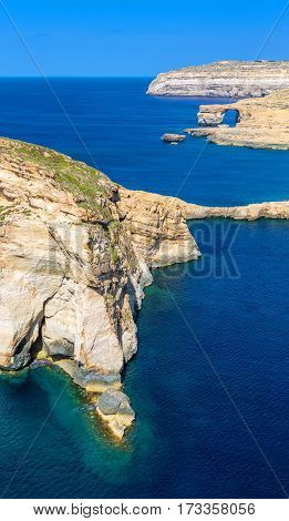 Gozo Malta - The Fungus Rock and the Azure Window at Dwejra bay on a beautiful summer day with clear blue sky sea water