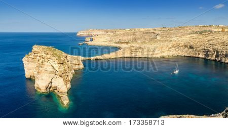 Gozo Malta - Panoramic view of the beautiful Fungus rock with the Azure Window and sail boat at Dwejra bay on a beautiful summer day with clear blue sky