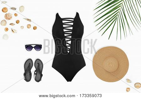 Flat lay beach accessories: swimsuit sunglasses hat sandals with palm branches and shells. Top view on white background.