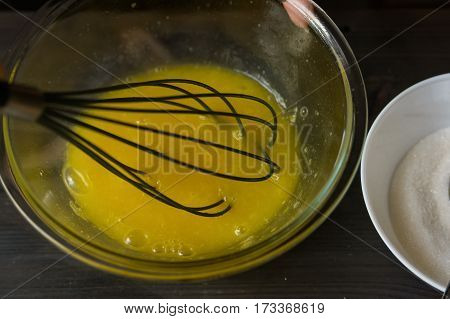 Hands mixing egg yolks with whisk in bowl