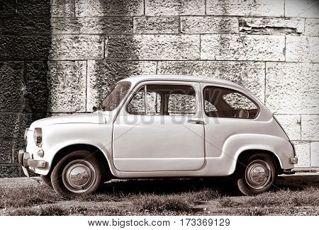 PULA, CROATIA - DECEMBER 9, 2016: Zastava 750 classic white color oldtimer supermini car parked on grass against old wall in Pula Croatia.