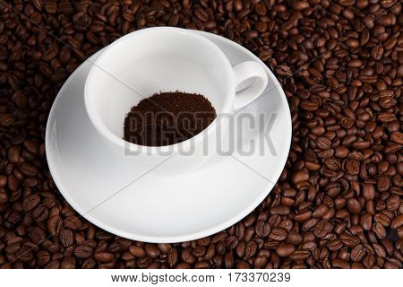 cup with ground coffee at coffee beans