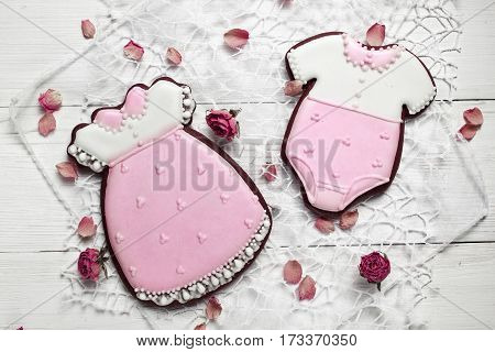 Cookies With Glaze In The Form Of Dress And Baby Body With Petals Of Dried Roses. On White Wooden Su