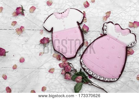 Cookies With Glaze In The Form Of Dress And Baby Body Withpetals Of Dried Roses. On White Wooden Sur