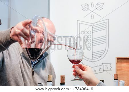 BELGRADE SERBIA - FEBRUARY 25 2017: Red wine being poured into a glass for a wine tasting during the 2017 Belgrade Tourism Fair