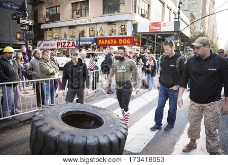NEW YORK - 11 NOV 2016: US Marine veteran Guy Valentino attempts the Guinness World Record for fastest one mile tire flipping of 450lb tire on 5th Ave at the Americas Parade on Veterans Day.