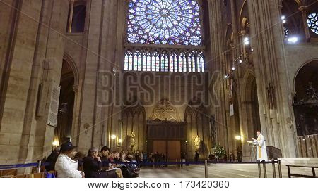 Paris, France - October, 14, 2016: Notre Dame de Paris cathedral interior with prayers listening a sermon from a French cardinal Andre Vingt-Trois.