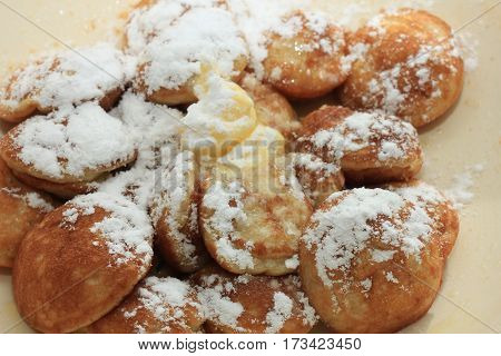 Poffertjes Dutch small fluffy pancakes served with powdered sugar and butter.