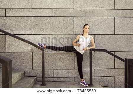Fitness beautiful woman with freckles on her face drinking water and sweating after exercising in city. Female athlete after work out. looking at camera and smilling.