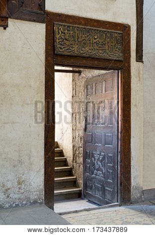 Cairo, Egypt - February 25, 2017: Wooden aged decorated door and beige plaster wall leading to stone staircase, Zeinab Khatoun historic House, Medieval Cairo, Egypt