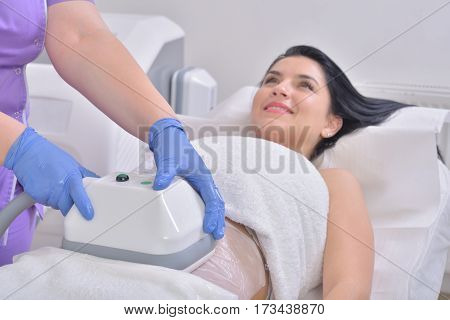 Pretty young woman getting cryolipolyse fat treatment in professional cosmetic cabinet