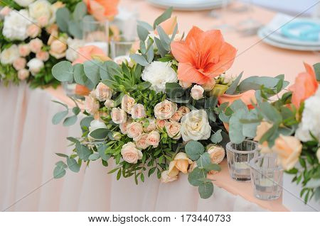Newlyweds table decorated with bouquet and candles, in peachy colours with monogram