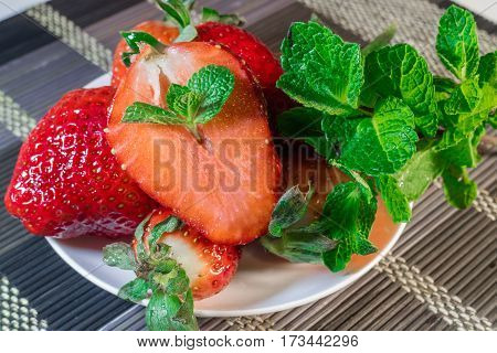 Strawberries with peppermint on a white plate