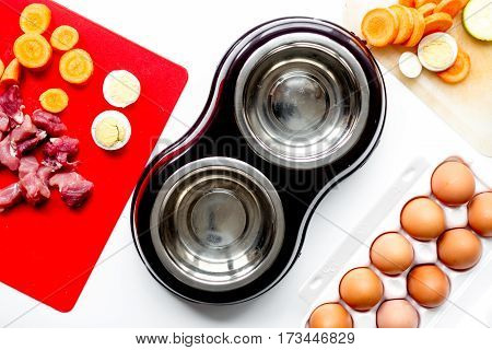 Dry dogfood, eggs, raw meat, fresh carrot and courgette on kitchen table background top view
