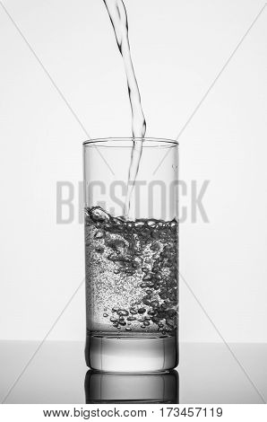 pouring sparkling water on glass on white background