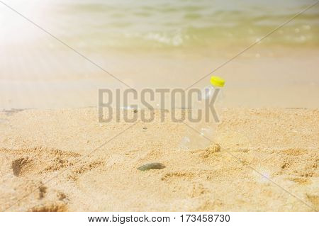 Bottle emtry on the sand behind beach with sunlight.