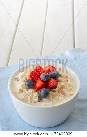Bircher Muesli with Fresh Strawberries and Blueberries on Top with Copy Space Vertical