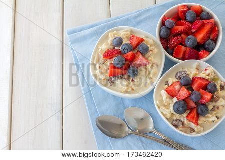 Bircher Muesli with Fresh Berries on White Wooden Table from Above with Copy Space