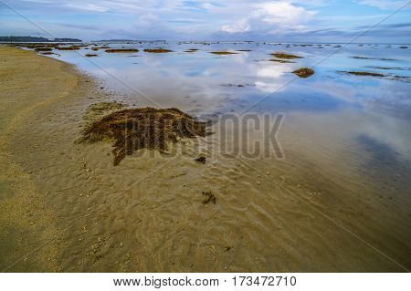 Calm sea,reflection and cloudy sky during low tide. Reflection of the vibrant sky and moving cloudy.