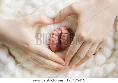 Legs newborn baby and Mama's arms heart