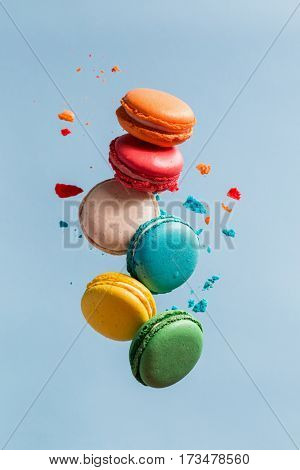 Different types of macaroons in motion falling on light 
blue background. Sweet and colorful french macaroons falling or flying in motion. 
