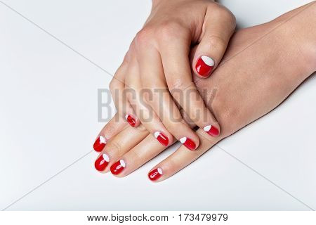 Close-up shot of young femle hands with red and white nail manicure. Copy space.