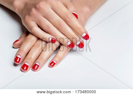 Close-up shot of young femle hands with red and white nail manicure. Copy space.