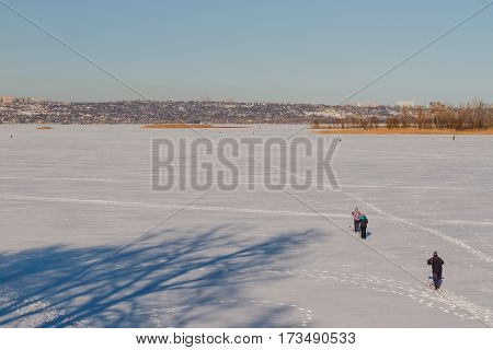 Bright frosty winter day. Frozen River Volga. Group of people skiing.