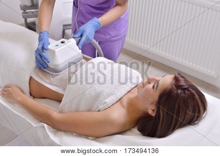 Pretty young woman getting cryolipolyse fat treatment in professional cosmetic cabinet