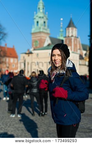 Young woman tourist in the city of Kracow , Poland, visiting the city and taking a picture in front of a famos church.