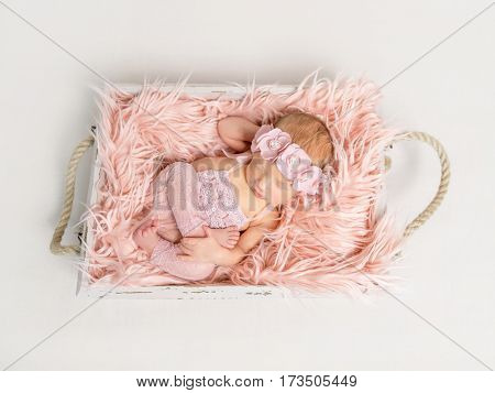 Lovely small girl sleeping in funny pose dressed in pinked laced suit, topshot