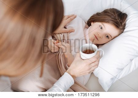 Thats for you. Cheerless sick girl lying in bed while her loving mother sitting nearby and taking care of her