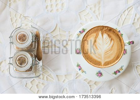 Vintage latte art coffee on table with sugar