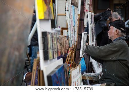 PARIS FRANCE - MARCH 8 2015: Artists and artworks on Place du Tertre in Montmartre. Portrait of the painter at work.
