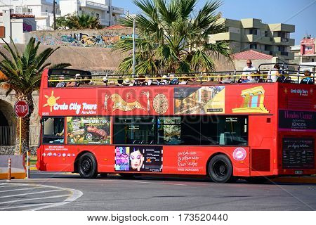 HERAKLION, CRETE - SEPTEMBER 19, 2016 - Passengers on a red open topped tour bus parked near the port Heraklion Crete Greece Europe, September 19, 2016.