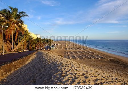 View on the beach Playa de Morro Jable with sand dune a promenade and the ocean on the sunset. Morro Jable Fuerteventura Spain - 14.02.2017.