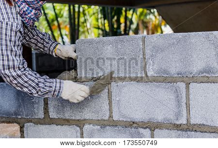 Bricklayer putting down another row of bricks in site