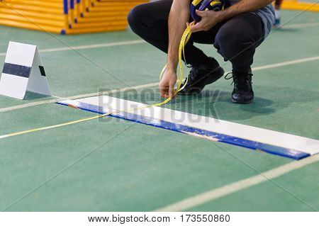 An official taking measure of long or triple jump on track and field competition