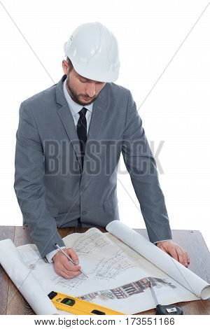 Engineering duties. Vertical shot of a mature male businessman architect in a hardhat working on building plans on blueprints isolated on white business new occupation architectural project planning